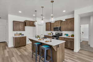 Kitchen with stainless steel appliances, light wood-type flooring, light countertops, hanging light fixtures, and recessed lighting