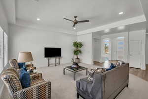 Living room with a tray ceiling, a ceiling fan, recessed lighting, and carpet