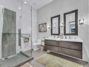 Bathroom featuring double vanity, a shower stall, and light wood-style flooring