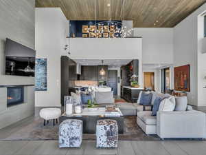 Living area with a high ceiling, wooden ceiling, a chandelier, a tile fireplace, and recessed lighting