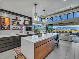 Kitchen with modern cabinets, decorative light fixtures, brown cabinetry, open shelves, and open floor plan