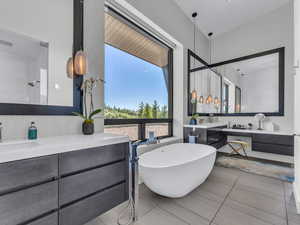 Full bath with vanity, a freestanding tub, and light tile patterned flooring
