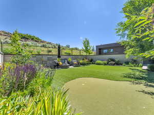 View of community featuring a patio area, a fenced backyard, and an area to practice putting