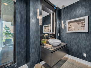 Bathroom with vanity, wallpapered walls, and wood finished floors