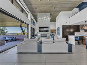 Living area with a towering ceiling, recessed lighting, light tile patterned floors, a chandelier, and a fireplace