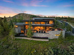 Back of property at dusk featuring a standing seam roof, a metal roof, a patio area, a fire pit, and roof mounted solar panels