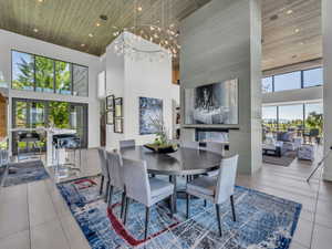 Dining space with a high ceiling, a large fireplace, light tile patterned floors, plenty of natural light, and recessed lighting