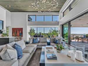 Living area featuring wooden ceiling, a high ceiling, healthy amount of natural light, and a chandelier