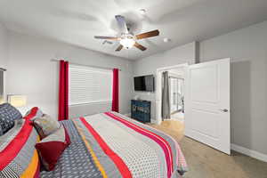 Bedroom featuring light colored carpet, multiple windows, and a ceiling fan