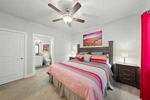 Bedroom with light carpet, connected bathroom, and a ceiling fan
