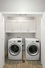 Laundry room with washer and dryer, cabinet space, and wood finished floors