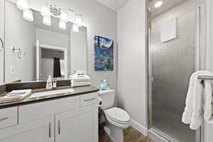 Full bathroom with a shower stall, wood finished floors, and vanity