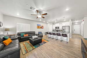 Living room featuring ceiling fan, arched walkways, light wood finished floors, and recessed lighting