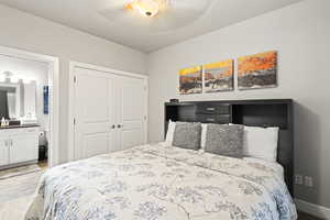 Bedroom with a closet, wood finished floors, ensuite bath, and ceiling fan