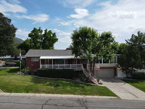 Ranch-style home featuring driveway, a front yard, an attached garage, stairway, and covered porch