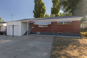 Ranch-style house featuring concrete driveway, brick siding, a front yard, and an attached garage