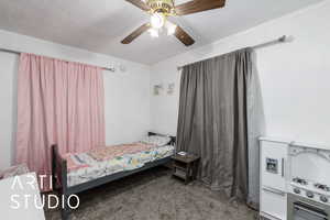 Bedroom with carpet floors, ceiling fan, and a textured ceiling