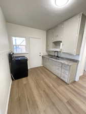 Kitchen featuring black / electric stove, light wood-type flooring, and gray cabinets