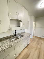 Kitchen featuring light wood-style floors, white cabinets, and light stone countertops