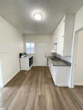 Kitchen with white appliances, white cabinetry, and light wood-style floors