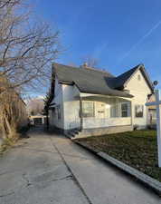 View of front of home with a shingled roof, driveway, an outdoor structure, and a chimney