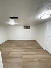 Finished basement featuring a textured ceiling and light wood finished floors