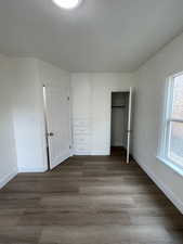 Unfurnished bedroom featuring dark wood-style flooring and a closet