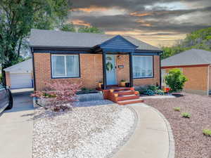 View of front of home with brick siding, a shingled roof, and a garage