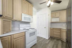 Kitchen featuring white appliances, light brown cabinets, light countertops, and a ceiling fan