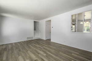 Unfurnished room with stairway, wood finished floors, and a chandelier