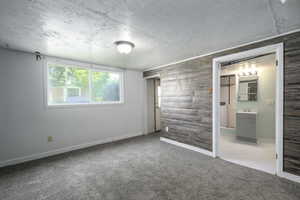 Unfurnished bedroom featuring a textured ceiling, carpet flooring, and connected bathroom