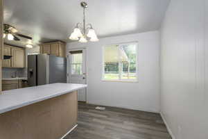 Kitchen with appliances with stainless steel finishes, light countertops, a chandelier, dark wood-style flooring, and hanging light fixtures