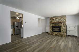Unfurnished living room with dark wood-style flooring, a fireplace, and ceiling fan