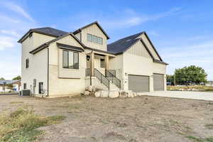 Modern inspired farmhouse with board and batten siding, concrete driveway, a shingled roof, an attached garage, and stone siding