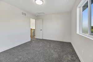 Unfurnished room with attic access and dark colored carpet