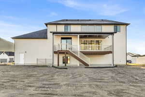 Rear view of property with a patio area, stairway, stucco siding, and roof with shingles