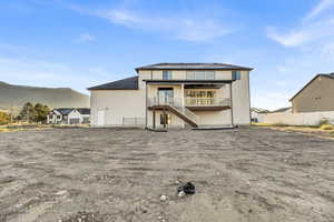 Rear view of house featuring a patio, stairs, a mountain view, a balcony, and stucco siding