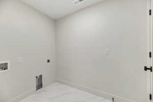 Washroom with marble finish flooring, washer hookup, and hookup for an electric dryer