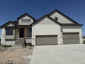 Modern farmhouse with board and batten siding, concrete driveway, an attached garage, covered porch, and stone siding