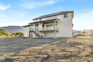 Back of house featuring stairway, stucco siding, a deck with mountain view, and a patio