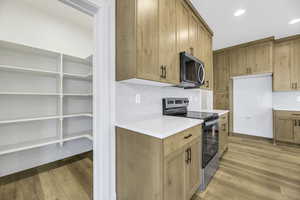 Kitchen featuring stainless steel appliances, tasteful backsplash, light wood-style flooring, recessed lighting, and brown cabinetry