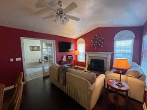 Living room with lofted ceiling, a ceiling fan, and a fireplace