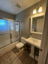 Bathroom featuring tile patterned floors and bath / shower combo with glass door