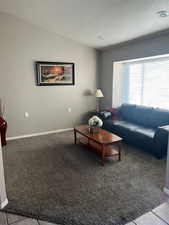 Carpeted living area featuring baseboards and lofted ceiling