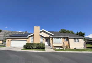 Ranch-style house with a chimney, solar panels, driveway, brick siding, and a mountain view