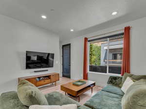 Living area featuring light wood-style floors and recessed lighting.