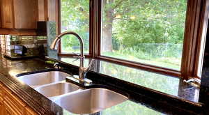 Kitchen view of backsplash, dark stone countertops, and brown cabinetry
