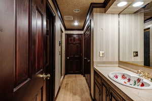 Bathroom featuring vanity, ornamental molding, and wood-type flooring