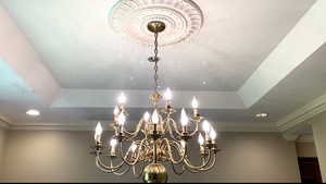 Detailed view of crown molding, a chandelier, and recessed lighting in dining room