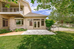 Doorway to property featuring a balcony, a patio, brick siding, and french doors